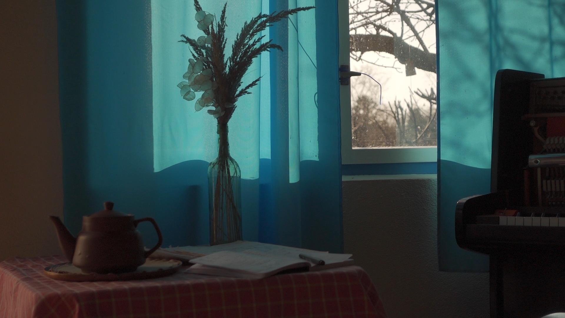 A quiet corner featuring a piano, fresh flowers, and soft natural light.