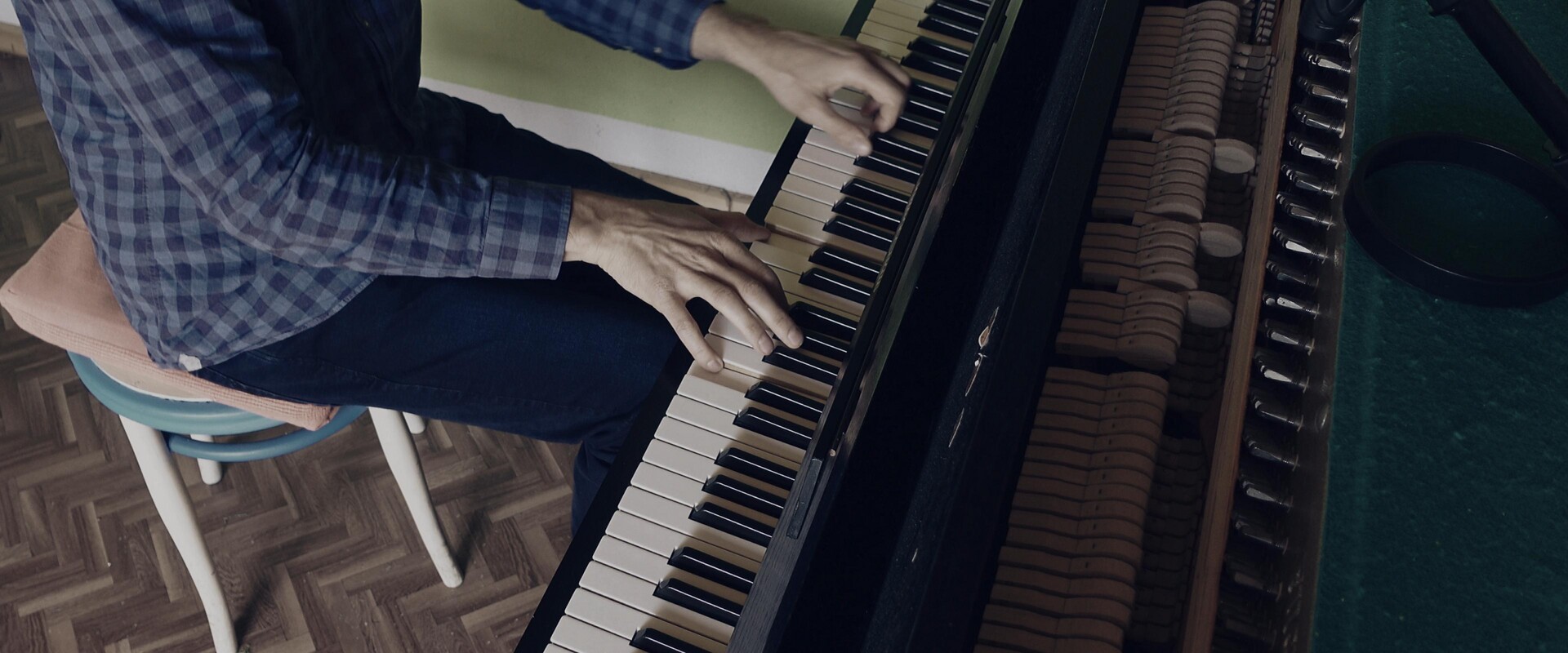 Focused hands playing the keys of a dark piano.